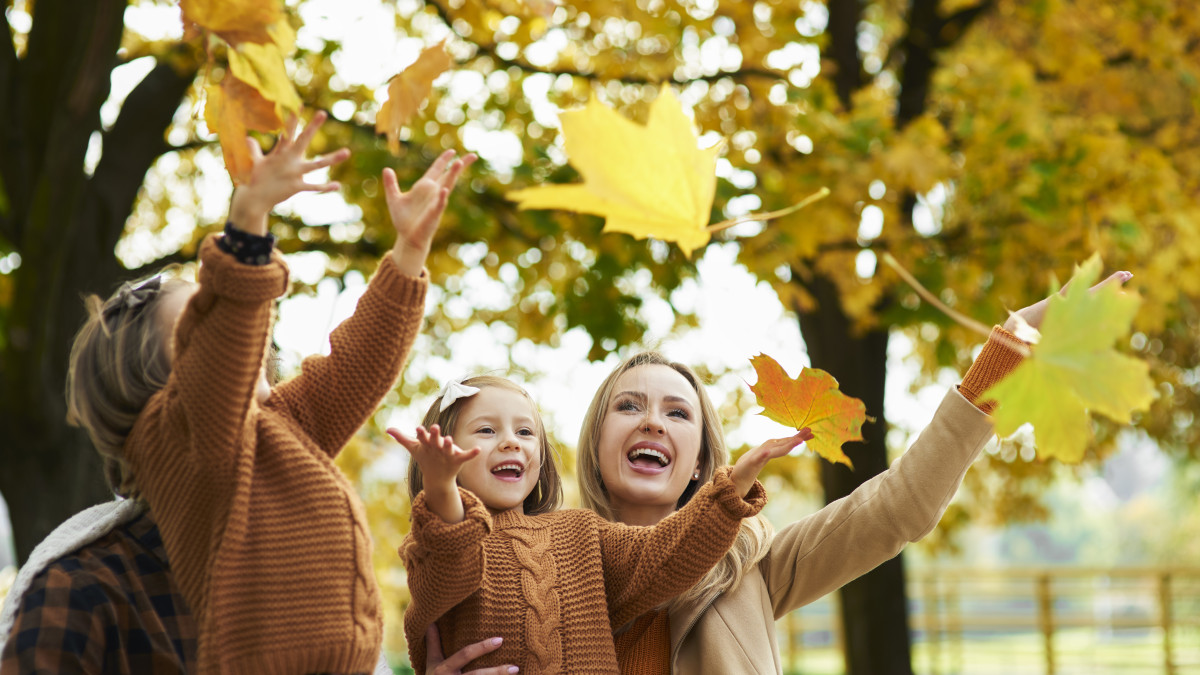 une famille joyeuse joue avec les feuilles mortes en automne